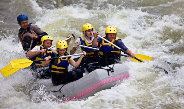 Group of five people whitewater rafting in river