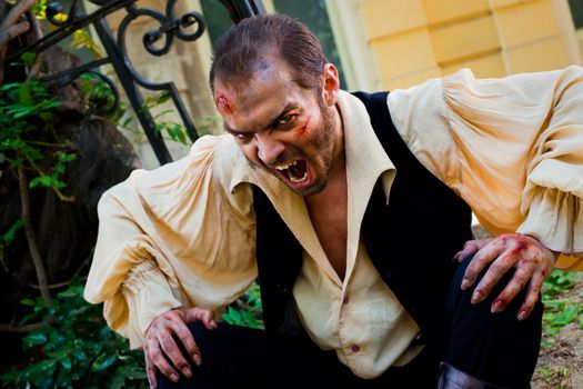 Evil male vampire with wounded face, roaring scary at camera