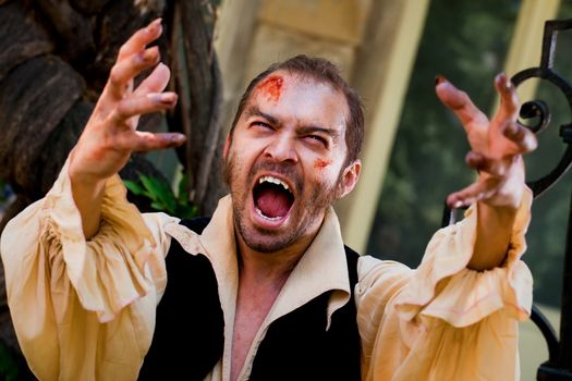 Wounded male vampire raising his arms and screaming