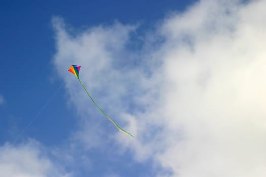 Colorful kite in flight against a blue sky with clouds