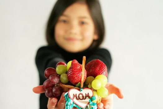 Little girl with a small fruit basket for mom