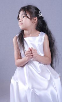 Beautiful little girl in white satin gown . Part Asian, Scandinavian background.