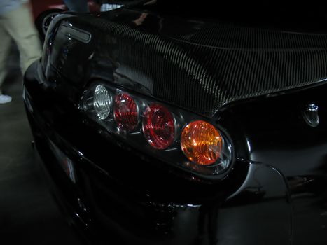 a closeup of a customized import sports car - complete with a carbon fiber trunk.