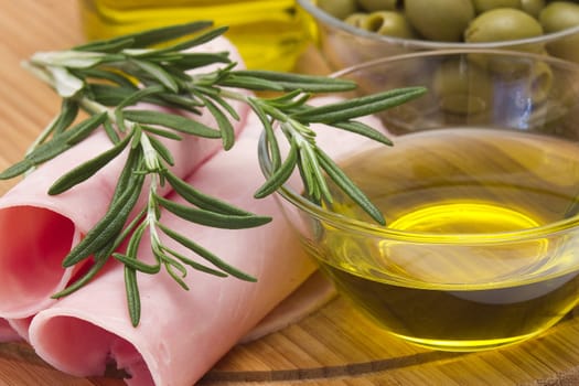 Rolled slices of ham, green olives and rosemary 