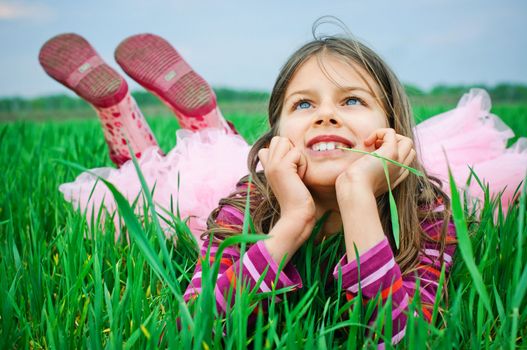 A beautiful little baby girl lying in the grass