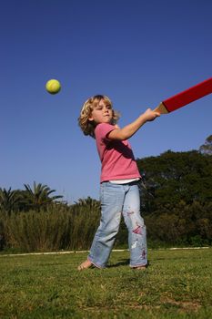 A young girl batting a ball, playing rounders (softball)