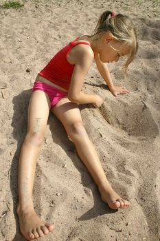 8 year old girl on the beach, writing in the sand. Vertical picture