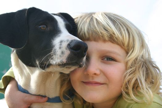 A 6 year old girl is cuddling her dog. Closeup of their faces