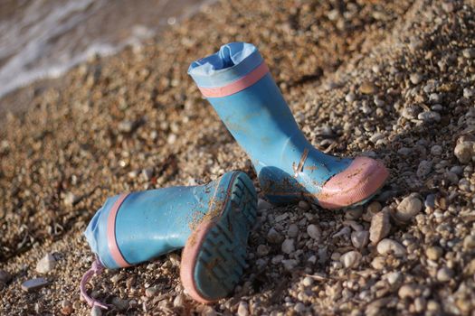 A pair of pink and blue childrens wellingtons left abandoned on the beach