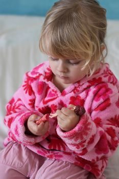 A little cute toddler is dressing her small plastic doll. Focus is on the doll