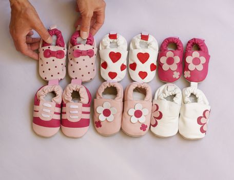 Hands organising six pairs of baby shoes into two lines