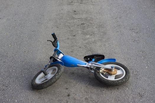 An old kids push bike is abandoned in the middle of the road