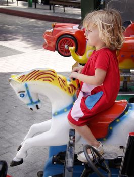Girl at the merry-go-round, riding a play horse