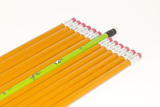 a green pencil sticking out form a crowd of plain yellow pencils