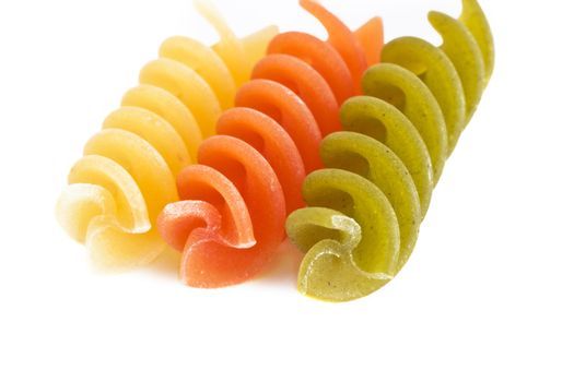 Three colorful raw fusillis on a white background