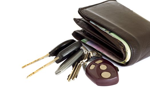 Car keys with an alarm along side a thick brown leather wallet on a white background