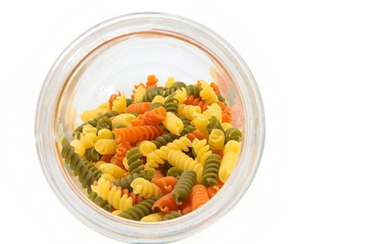 Colorful raw fusilli in a glass jar on a white background