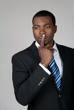 African American business man thinking and holding a finger on his lips.