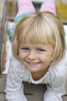 Portrait of a blond beautiful little 4 year old girl coming down the slide. Positive feeling.