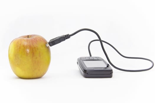 An apple connected to an mobile phone over a wire cable.