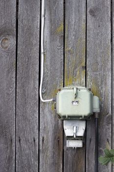 An old electricity supply box hanging on a wooden barn wall. Space for copy text