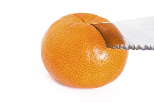 A sharpe knife cutting through a ripe mandarine orange