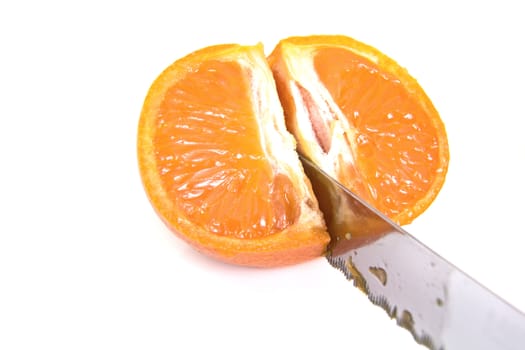 A sharpe knife cutting through a ripe mandarine orange