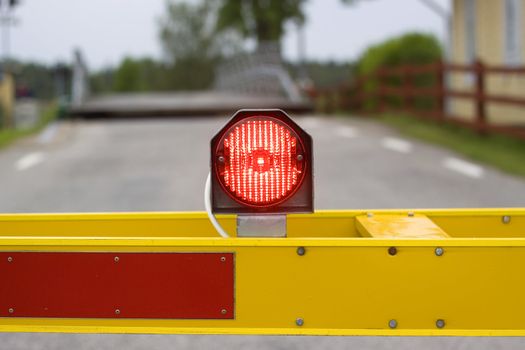 A red light on a yellow barrier, stopping traffic on a countryside road