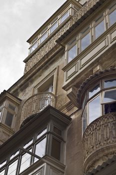 Facade with old wooden balconies reflecting the sky in Valletta, Malta, Europe