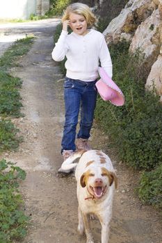 A young girl walking her dog in the countryside. Unsharp focus on dog