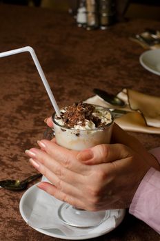 Closeup of female hands holding cup of latte