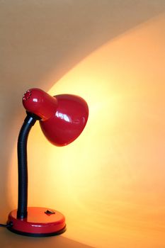 Modern red luminous desk lamp on yellow background with copy space