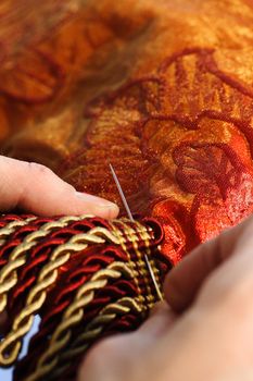 Craftsman working on a curtain with a needle