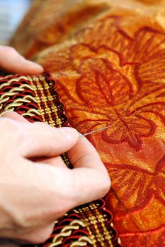 Craftsman hands working on a curtain with a needle