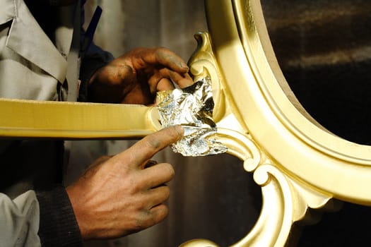 Hands working on wood with gold film