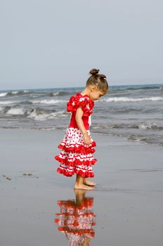 Child in fine red and white dress on the beach