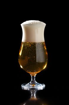 Glass of foamy beer on a black background