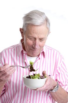 Senior man eating a green salad out of a bowl