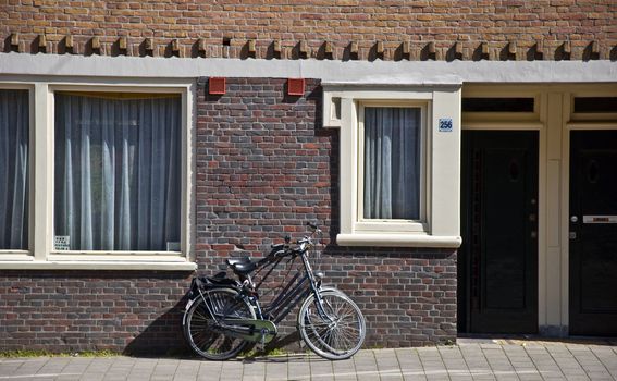 Bicycle leaning against the Dutch residential building. Urban scene. Spring
