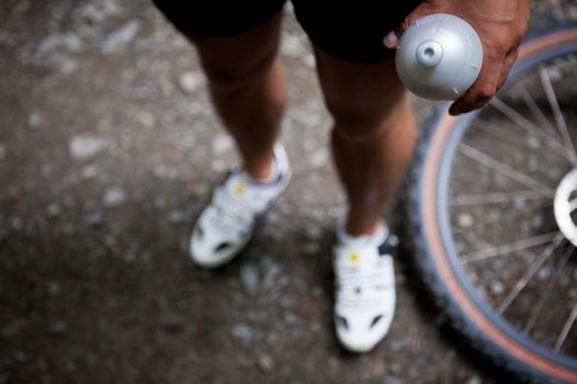 Mountain biking in a forest - bikers on a forest biking trail (shallow DOF, focus on the bike wheel in the foreground)