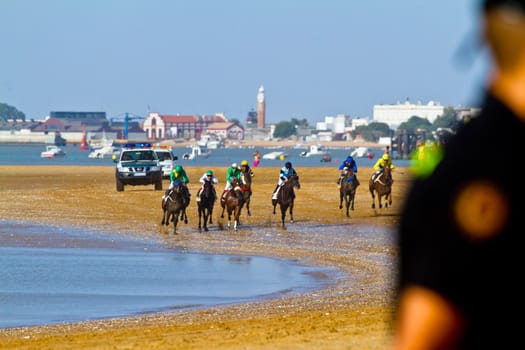 SANLUCAR DE BARRAMEDA, CADIZ, SPAIN - AUGUST 10: Unidentified riders race horses on Sanlucar de Barrameda beach on August 10, 2011 in Sanlucar de Barrameda, Cadiz, Spain.