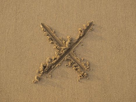 Sign of letter x drawn on wet beach sand