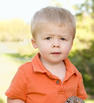 Cute Young Boy Portrait Holding Pine Cone in The Park.