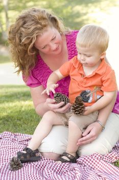 Attractive Mother and Adorable Son Talk about Pine Cones in The Park.