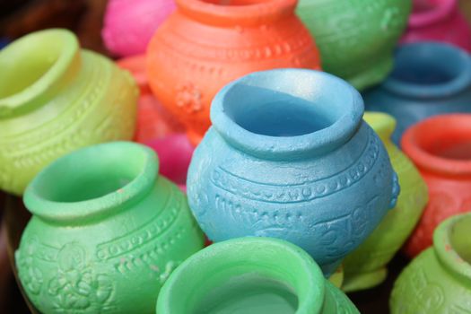 Small clay pots in various colors with religious text inscribed for Diwali festival celebration rituals in India.