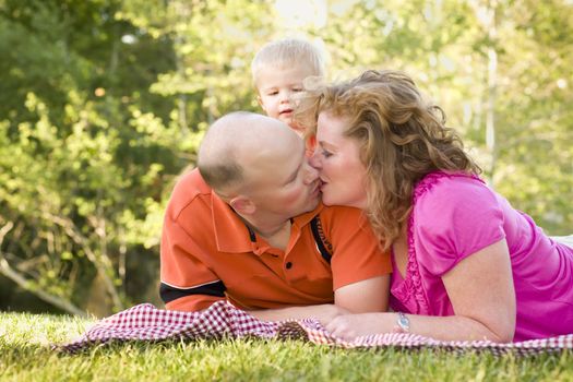 Affectionate Couple Kiss as Adorable Son Watches in the Park.