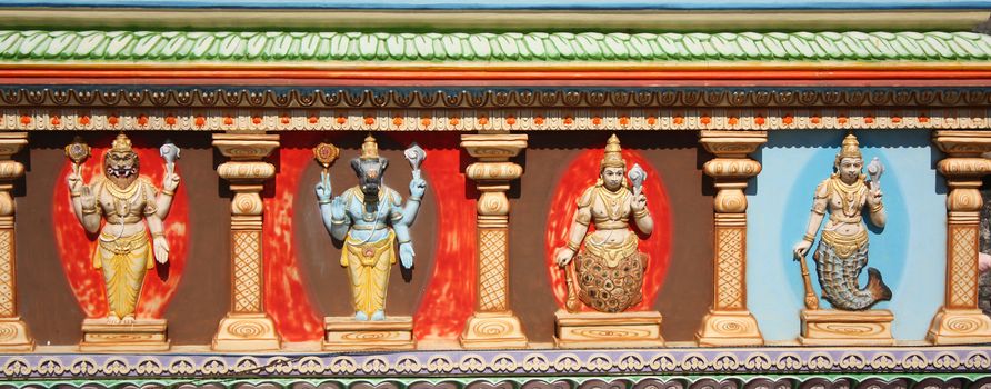 Colorful sculptures depicting avatars of hindu god Vishnu on a temple wall in India.
