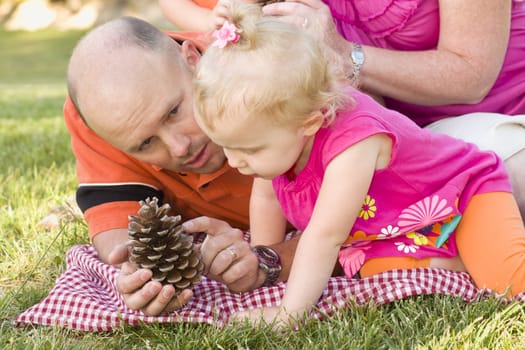 Handsome Father and Adorable Young Daughter Talk about Pine Cone in the Park.