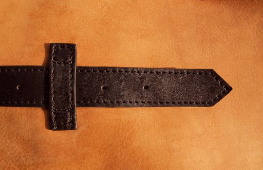 Leather belt on beige leather background