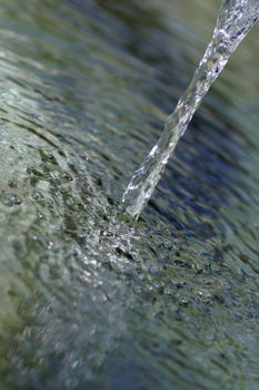 Crystal clear flowing water running into small well.